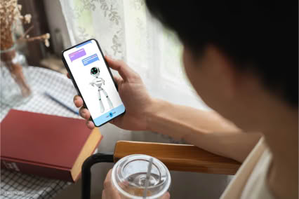 A person holding a smartphone displaying a cartoon character, with a book and a drink on a table nearby.